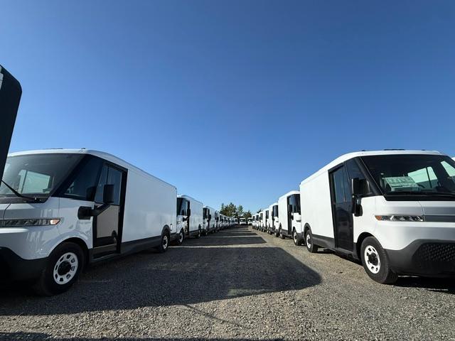 A long lineup of commercial electric delivery vans ready for service in a fleet depot